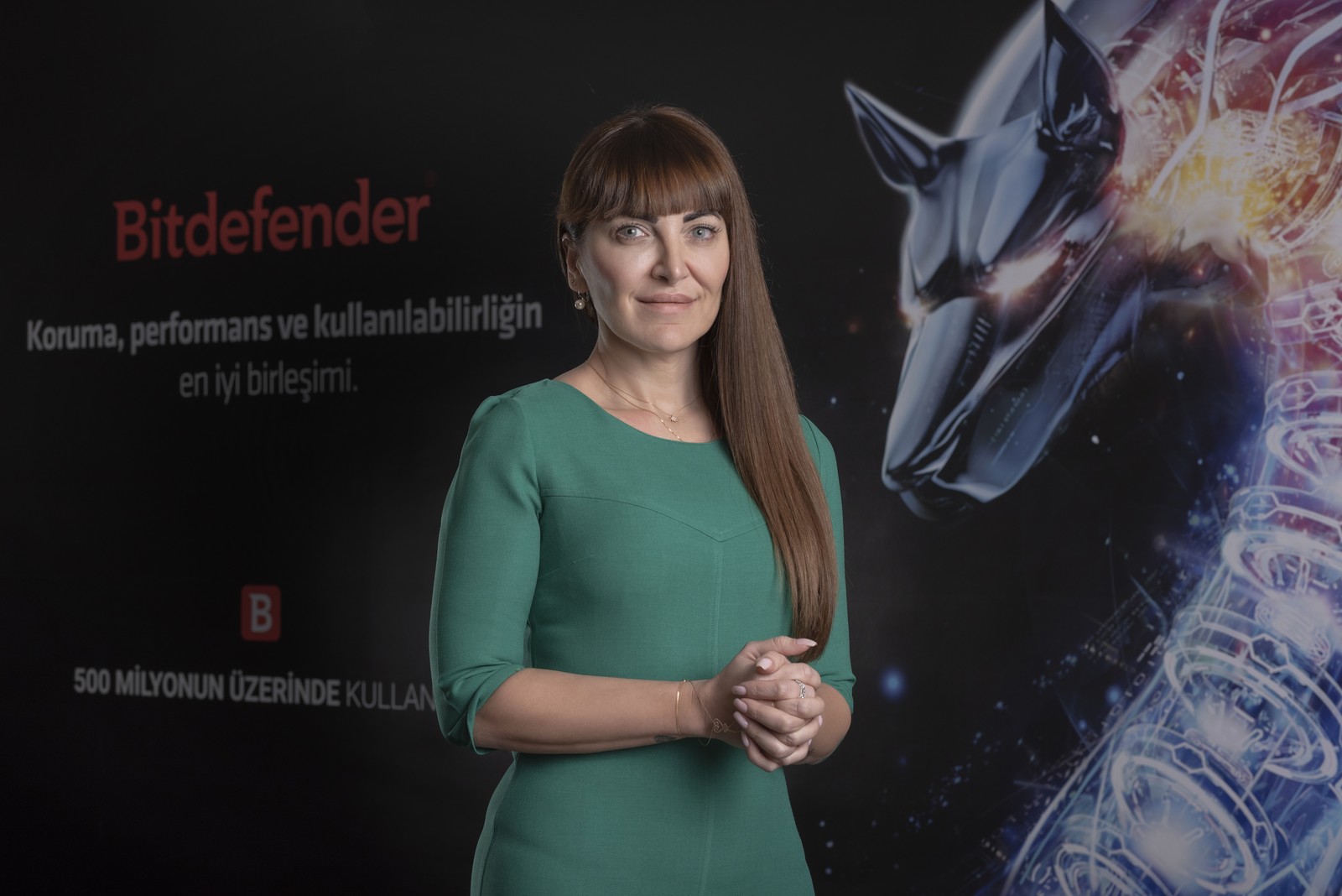 Bitdefender panosu önünde yeşil elbiseli şirket temsilcisi.
