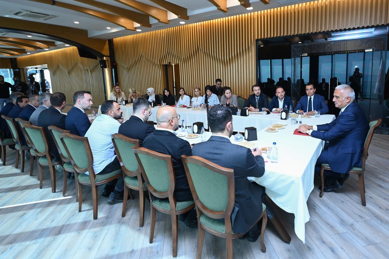 Resmî toplantıda masanın çevresinde oturan yetişkin katılımcılar.